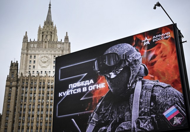 TOPSHOT - Russian Foreign Ministry building is seen behind a social advertisement billboard showing Z letters - a tactical insignia of Russian troops in Ukraine and reading "Victory is being Forged in Fire" in central Moscow on October 13, 2022. Five Russians drafted to fight in Ukraine, as part of the "partial" mobilization ordered in September, died after joining the army, authorities said, as similar announcements have multiplied in recent days. (Photo by Alexander NEMENOV / AFP) (Photo by ALEXANDER NEMENOV/AFP via Getty Images)